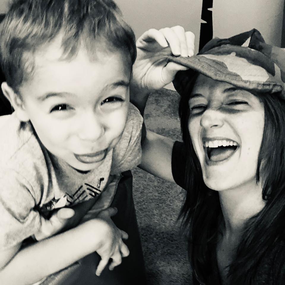 Nikki laughing with her son, who is wearing her hat